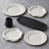 Coffret Minéral d’hiver : quatre assiettes blanches aux bords striés ou rocheux, un plat rectangulaire et une saucière noirs.