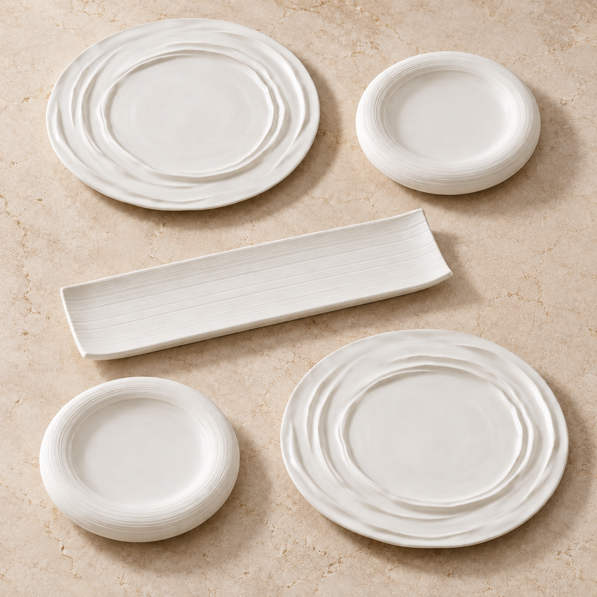 Ensemble blanc avec deux grandes assiettes à relief ondulé, deux petites assiettes à bord strié et un plat rectangulaire.