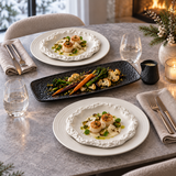 Table hivernale avec assiettes blanches à relief minéral, plat rectangulaire noir de légumes et petite saucière noire.