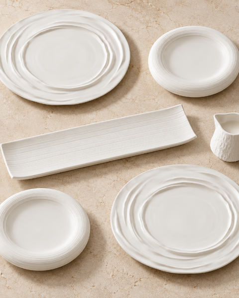 Coffret Blanc de fête : deux grandes assiettes ondulées, deux petites assiettes striées, un plat rectangulaire et une saucière blancs.